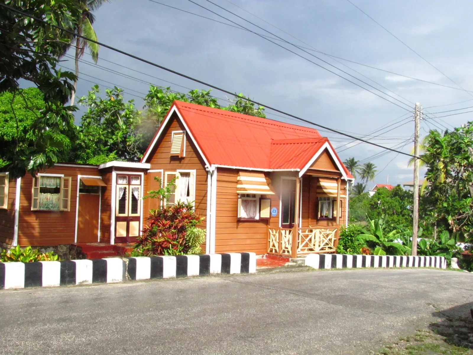 Barbadian chattel house seen from the side, showing a steep symmetrical gable roof with short overhangs