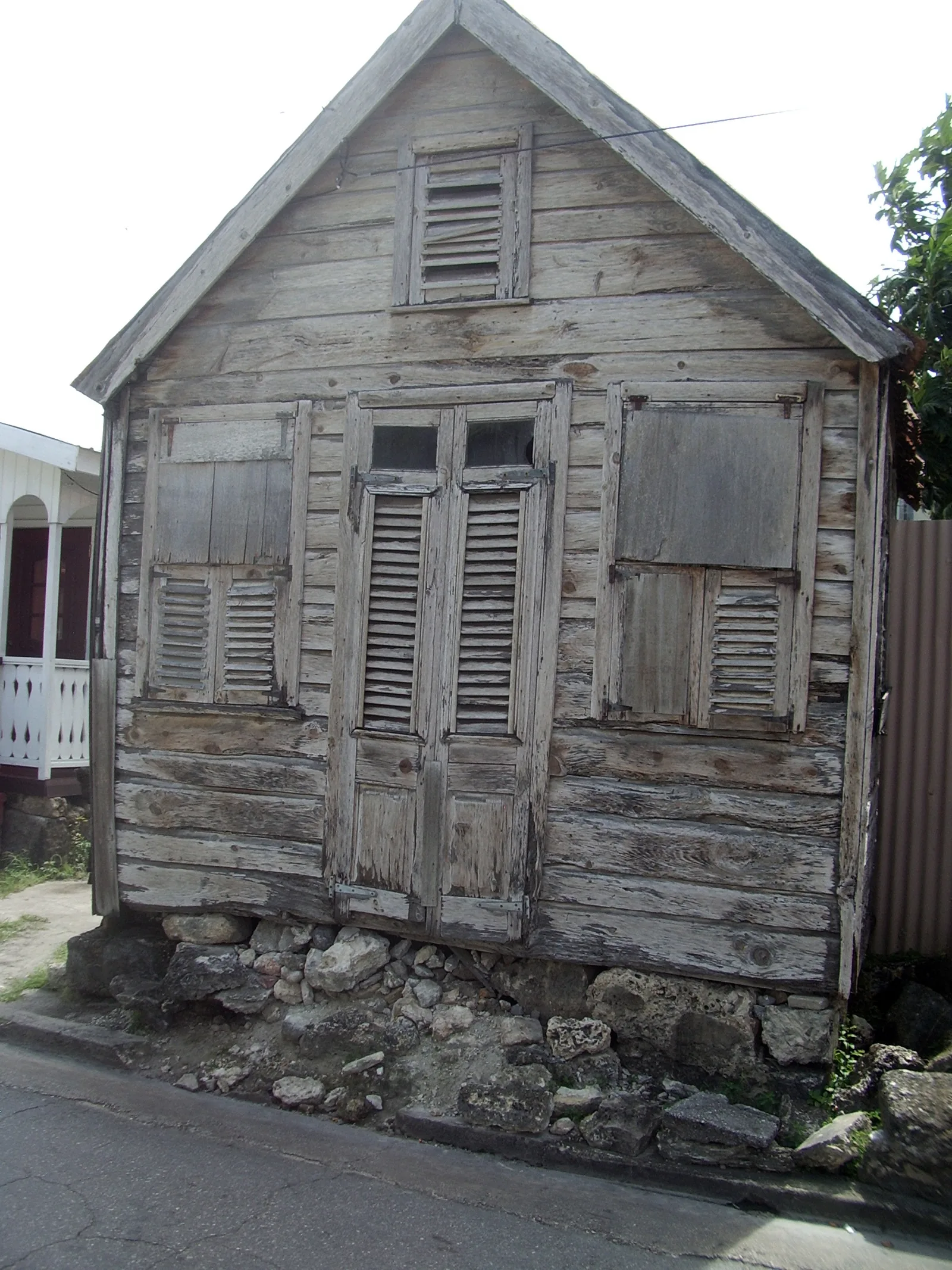 Close view of a weathered chattel house gable with louvred jalousie shutters
