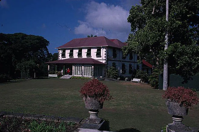 Francia Great House in St George, Barbados, on a terraced lawn: a masonry great house with a deep shaded veranda, shuttered windows and a hipped roof