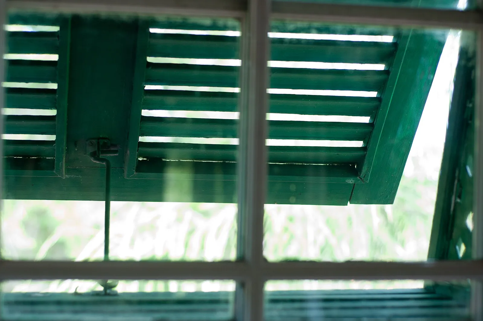 Close view of a green timber jalousie shutter propped open over a sash window at Sunbury Plantation House, Barbados